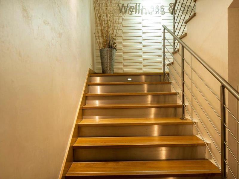 Drewniane schody z oświetleniem stopni prowadzące do dobrze oświetlonego spocznika.