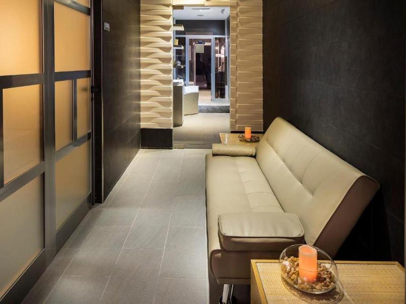 Nowoczesny korytarz hotelowy z długą beżową sofą i dekoracyjnymi elementami.