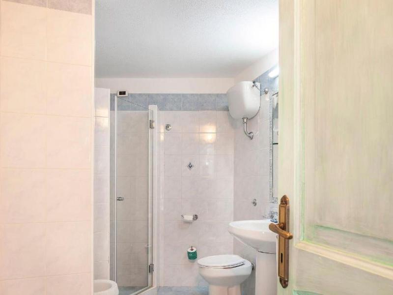 Mała łazienka z prysznicem, toaletą i umywalką w neutralnych kolorach.