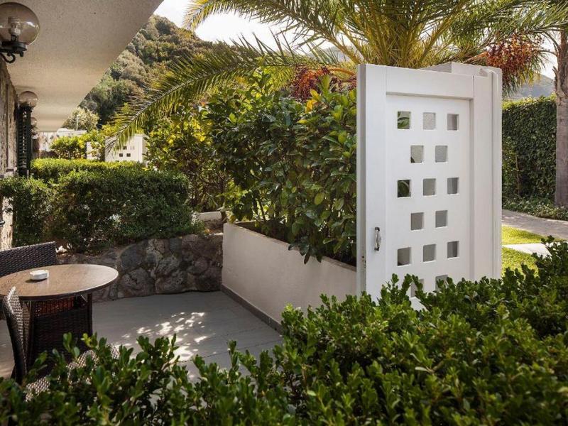 Taras z stołem i krzesłami obok prywatnego ogrodu z białymi drzwiami