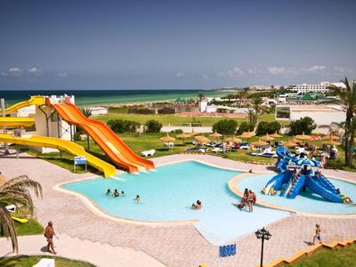 Wasserpark mit bunten Rutschen, blauem Pool, Palmen und blauem Himmel am Meer.