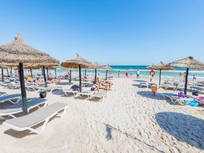 Plaża z białymi leżakami i parasolami przy czystym, niebieskim morzu i niebie.