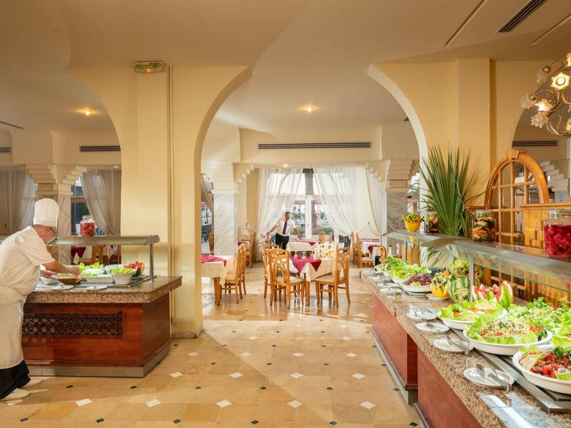 Restauracja hotelowa z kucharzem pracującym przy bufecie z świeżymi warzywami.