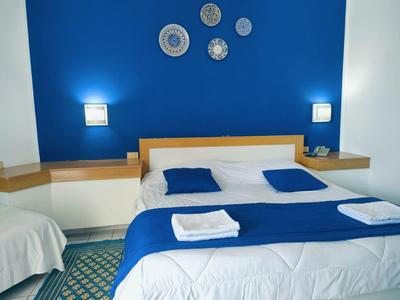 Pokój hotelowy z niebiesko-białym wystrojem, łóżkiem podwójnym i dekoracjami ściennymi z talerzy