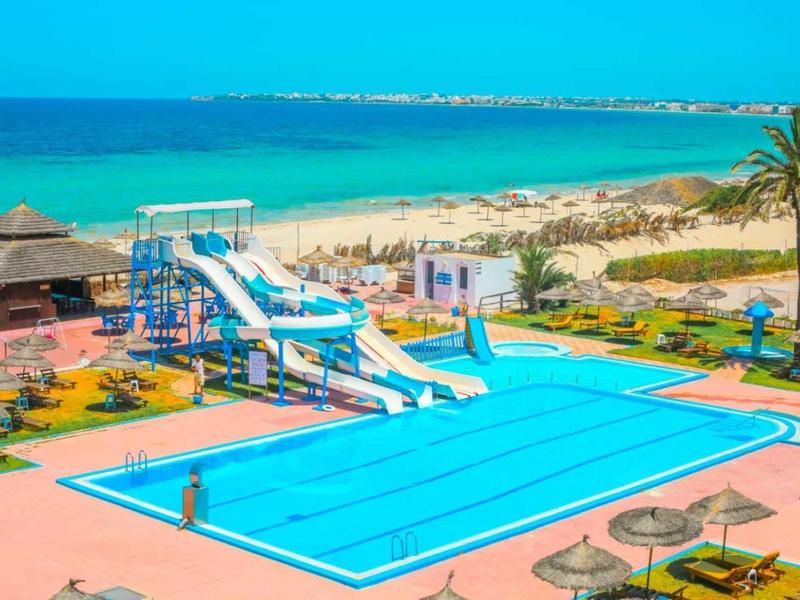 Zwembad met glijbanen, ligstoelen en uitzicht op het strand op een zonnige dag