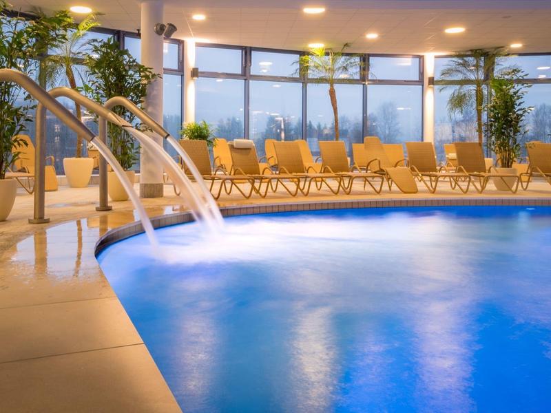 Hotelowy basen kryty z wodospadami i leżakami przy dużych panoramicznych oknach