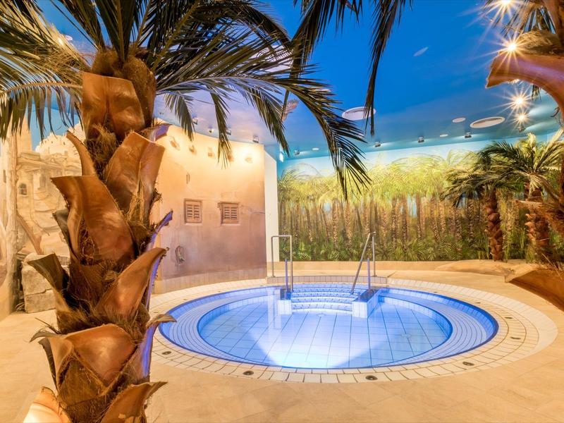 Okrągły basen na zewnątrz z palmami i śródziemnomorską dekoracją o zmierzchu