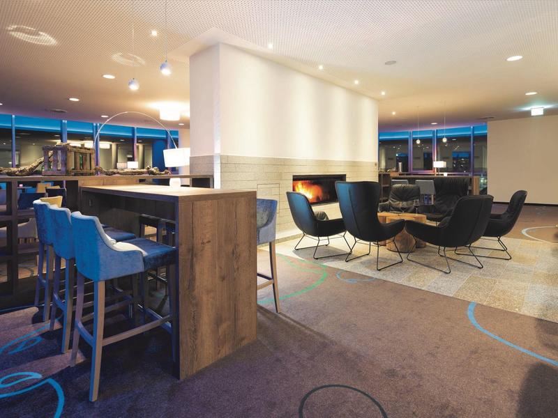 Nowoczesna strefa wypoczynkowa hotelu z barem i miejscami do siedzenia z fotelami.