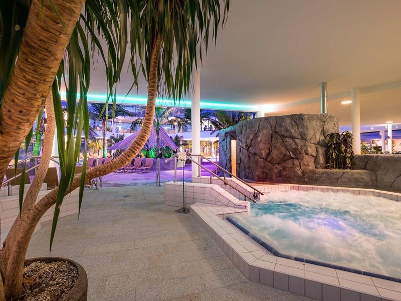 Wnętrze z jacuzzi, rośliną i pośrednim kolorowym oświetleniem w hotelu.