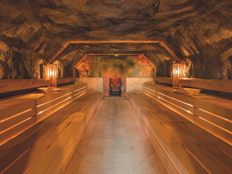 Przytulna strefa spa w jaskini z drewnianymi ławkami i oświetleniem świec.