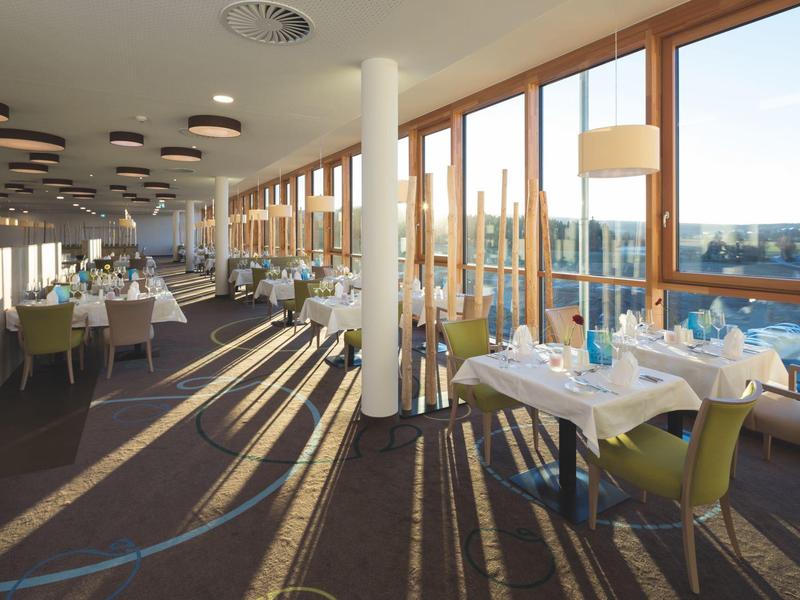 Jasna, nowoczesna jadalnia z dużymi oknami i dekoracją stołu w hotelu.