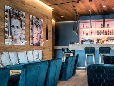 Moderner Hotelbarbereich mit Holzverkleidung, blauen Sesseln und stilvoller Beleuchtung.