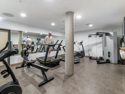 Moderner Fitnessraum mit Trainingsgeräten und Spiegelwand in einem Hotel.