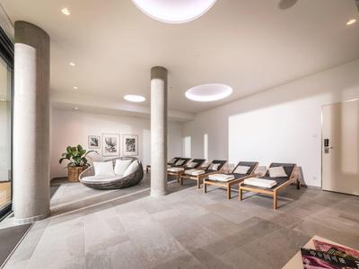 Nowoczesna, jasna poczekalnia z fotelami, okrągłymi kolumnami i minimalistycznym wystrojem.