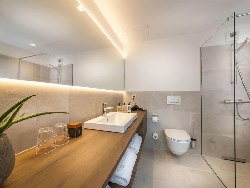 Nowoczesna łazienka z drewnianym blatem, umywalką, toaletą i prysznicem.