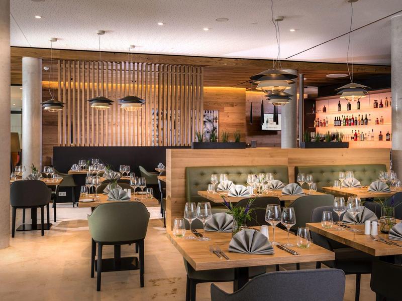 Nowoczesna restauracja z gustownie nakrytymi drewnianymi stołami i przytłumionym oświetleniem.