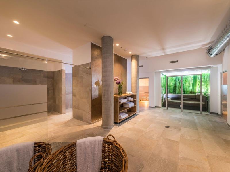 Jasne lobby hotelowe z kamienną podłogą, kolumnami i panoramicznymi oknami dla gości.