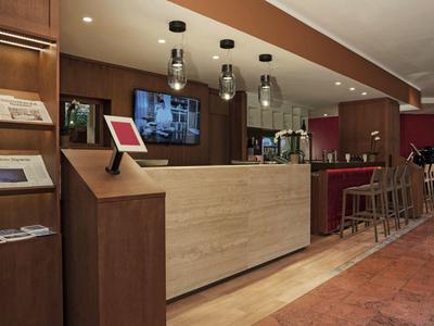 Reception d'hotel moderna con elementi in legno, sedute e illuminazione.