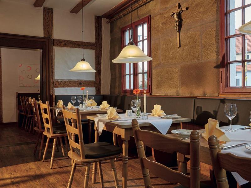 Przytulna jadalnia z drewnianymi meblami i nakrytymi stołami w ciepłym świetle.