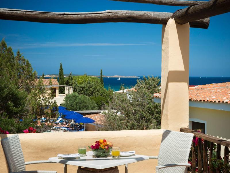 Balkon mit Tisch, Stühlen und Blick auf das Meer bei sonnigem Himmel.