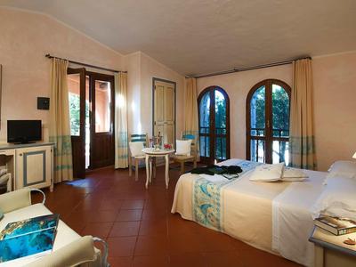 Zimmer mit zwei Betten, hellen Wänden, großen fenstern und terrakottafarbenem Boden.