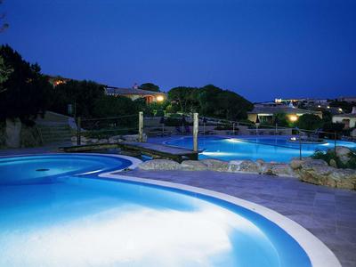 Beleuchteter Außenpoolbereich eines Hotels bei Nacht mit klarem Himmel.