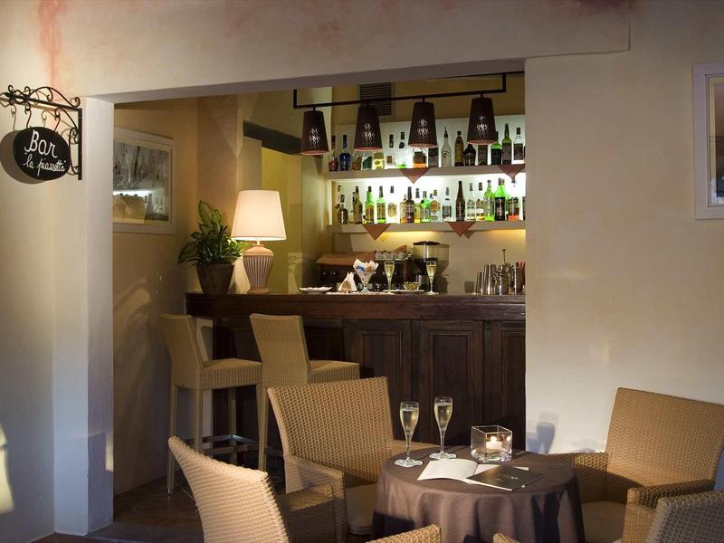 Gemütliche Bar mit Holzmöbeln, Weinflaschenregal, warmem Licht und gedeckten Tischen.