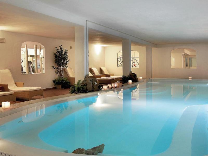 Innenpool mit Liegestühlen und warmem Licht in einer Hotelumgebung.