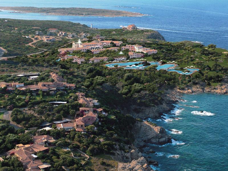 Luftaufnahme eines Küstenresorts mit Gebäuden, Pools und Felsen am Meer.