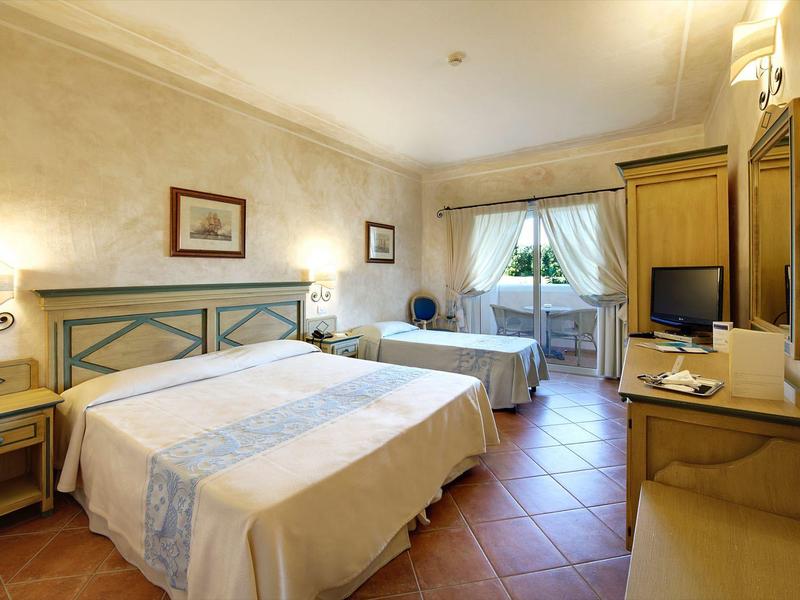 Helles Hotelzimmer mit zwei Betten, Sitzbereich und Fernseher an der Wand.