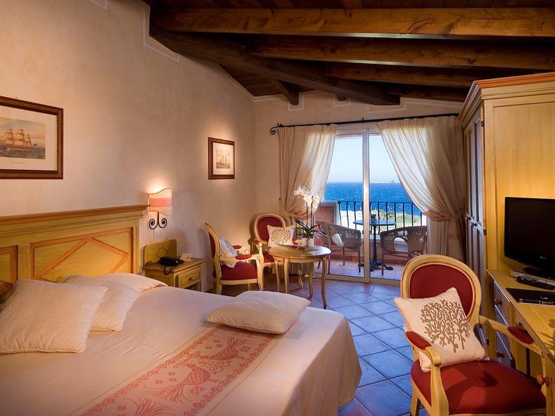 Gemütliches Hotelzimmer mit Holzbalkendecke, Doppelbett und Balkon mit Meerblick.