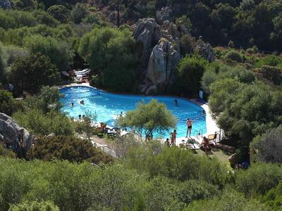 Ein natürlicher blauer Pool umgeben von dichtem grünen Buschwerk und Felsen.