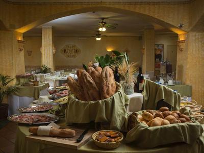 Buffet mit verschiedenen Brotsorten und Aufschnitt in warm beleuchtetem Raum mit Holzmöbeln.