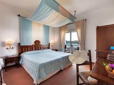 Gemütliches Hotelzimmer mit Doppelbett, Schreibtisch und Balkon mit Blick aufs Wasser.