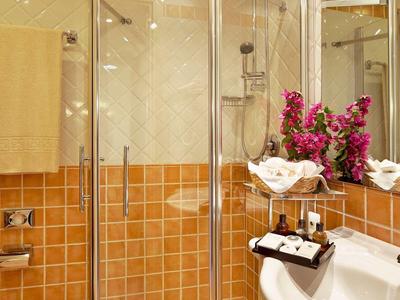 Kompaktes Badezimmer mit Dusche, orangefarbenen Fliesen und weißen Handtüchern