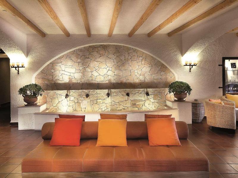 Modern eingerichteter Wohnraum mit Lederbank, bunten Kissen und Steinwandbeleuchtung.