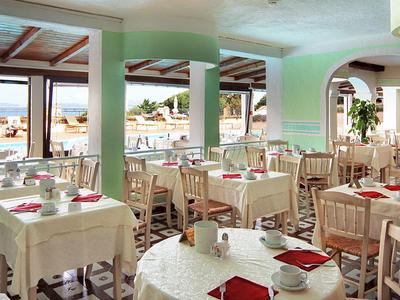 Helles, gemütliches Restaurant mit weißen Tischdecken und Ausblick auf das Meer.