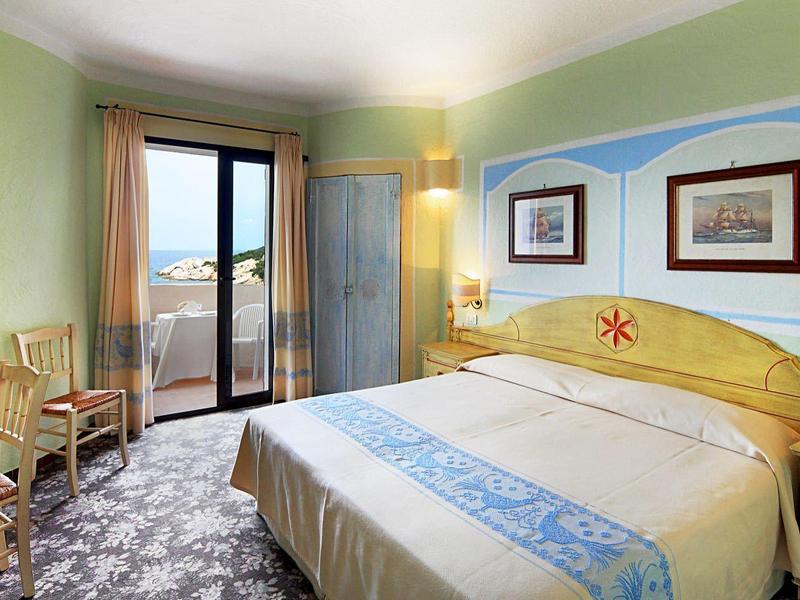 Hell eingerichtetes Hotelzimmer mit Doppelbett, Schreibtisch und Balkon mit Meeresblick.