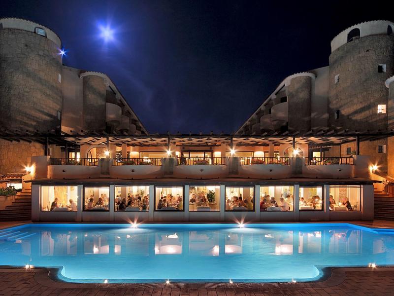 Beleuchteter Pool vor einem historischen Gebäude bei Nacht unter hellem Mondlicht.