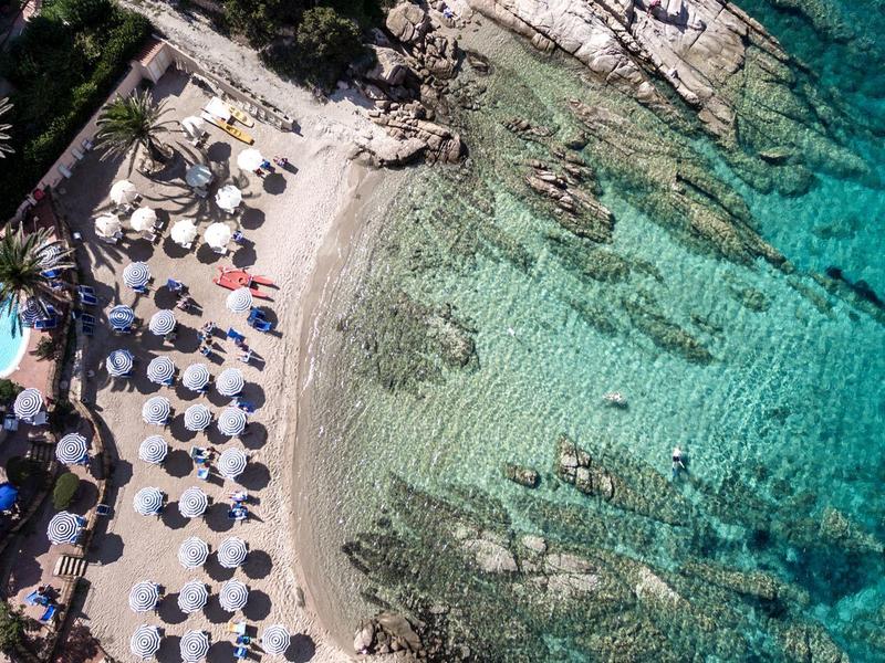 Vogelperspektive eines Hotels mit Pool, Sandstrand und klarem blaugrünem Wasser