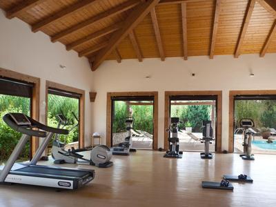 Moderner Fitnessraum mit Holzbalkendecke und Blick auf den Garten und Pool.