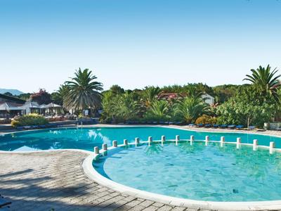Großer Hotelpool mit Sonnenschirmen, Palmen und Liegestühlen bei klarem Himmel.