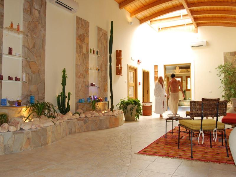 Heller Innenhof mit Steinwänden, Pflanzen, Sitzgruppe auf Teppich und Holzdecke mit Balken.