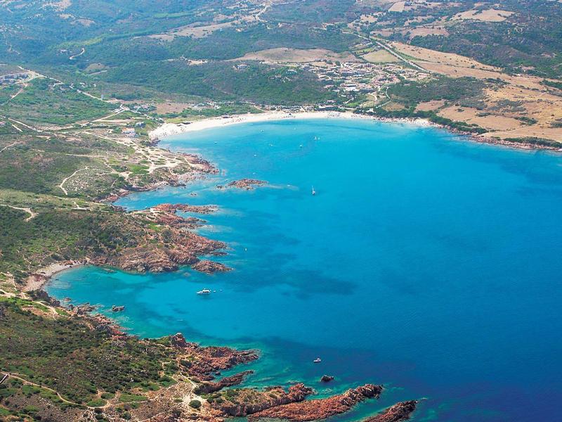 Landschaft mit einer großen Bucht, blauem Wasser, weißen Sandstränden und grüner Vegetation.