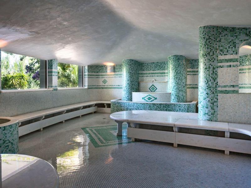 Helles, großes Ruhezimmer mit gebogenen weißen Bänken und blauen Mosaiksäulen.