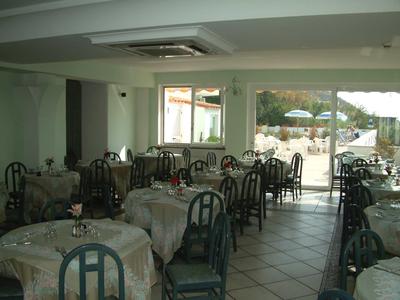 Innenraum eines Restaurants mit gedeckten Tischen, dunkelgrünen Stühlen und Blick auf Terrasse.