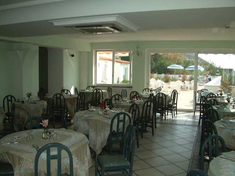 Innenraum eines Restaurants mit gedeckten Tischen, dunkelgrünen Stühlen und Blick auf Terrasse.