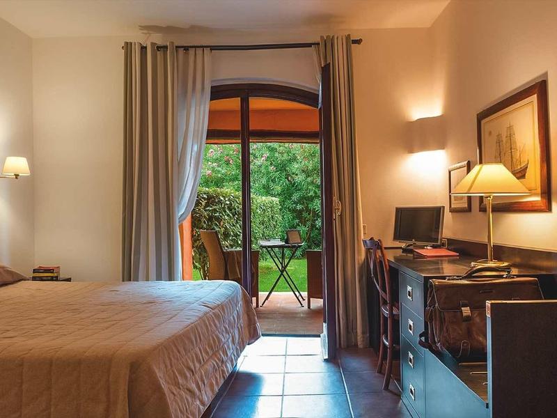 Gemütliches Schlafzimmer mit Doppelbett, Holzmöbeln, Vorhängen und Blick auf grünen Garten.