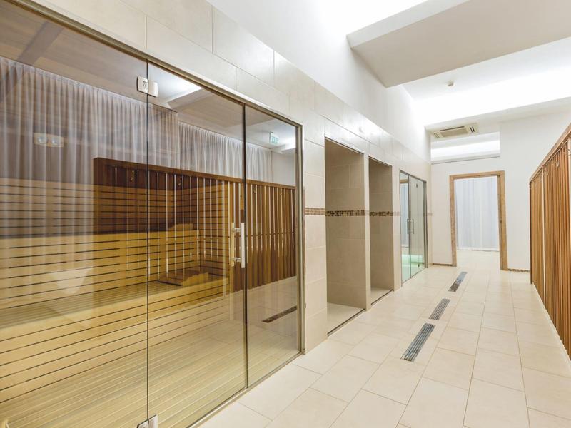 Espace bien-être moderne avec saunas en verre et couloir lumineux.