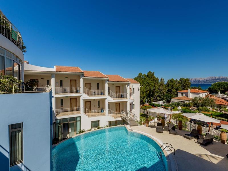 Hôtel avec grande piscine extérieure et chaises longues sous un ciel bleu